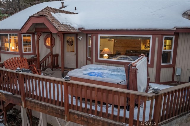 snow covered deck featuring hot tub deck surround