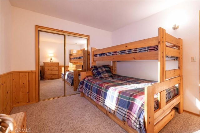 carpeted bedroom featuring a closet, a wainscoted wall, and wood walls