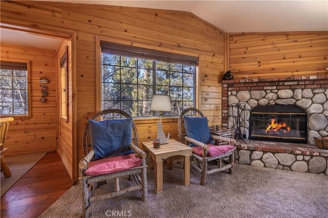 sitting room featuring vaulted ceiling, a fireplace, wood finished floors, and wooden walls