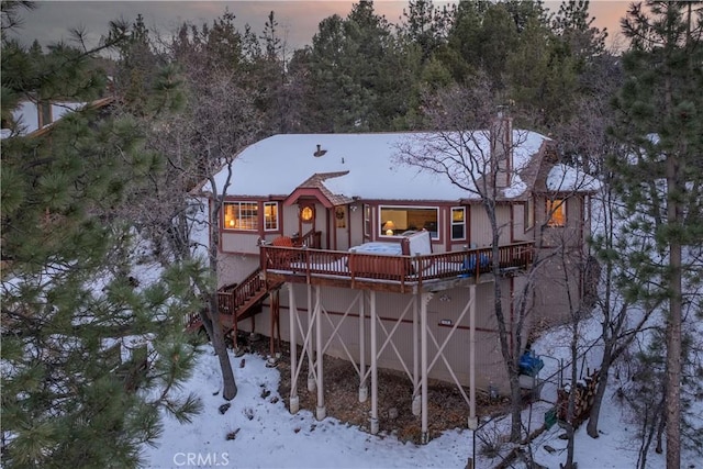 snow covered rear of property featuring stairway and a wooden deck