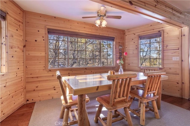 dining area with wooden walls and a ceiling fan