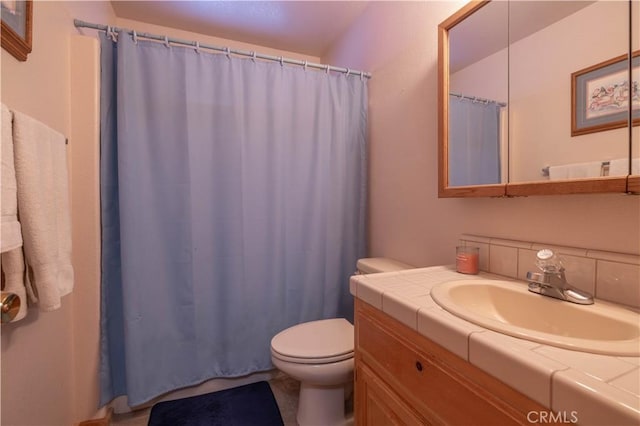 full bathroom featuring a shower with shower curtain, vanity, and toilet