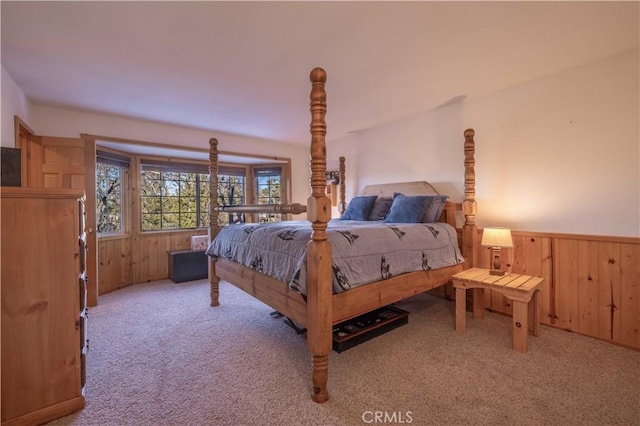 bedroom featuring light carpet, wood walls, and wainscoting