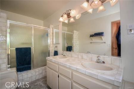 full bath featuring double vanity, a sink, and tiled shower