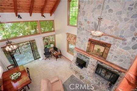 living area featuring high vaulted ceiling, a stone fireplace, wooden ceiling, carpet flooring, and beamed ceiling