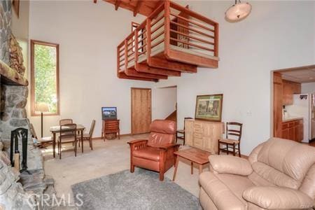 carpeted living room featuring a high ceiling and a fireplace