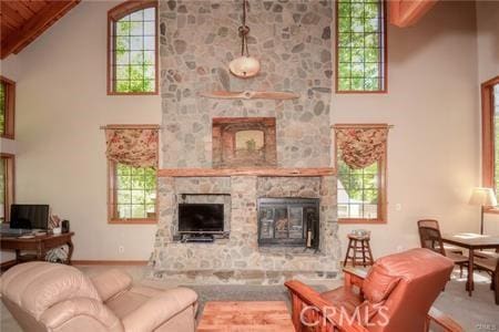 living area with baseboards, high vaulted ceiling, and a stone fireplace