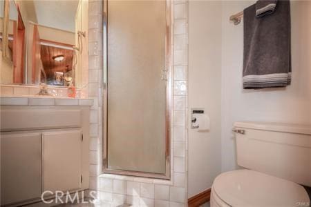 bathroom featuring toilet, a stall shower, and vanity