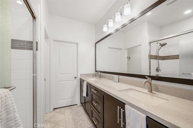 full bathroom featuring double vanity, a stall shower, a sink, and tile patterned floors