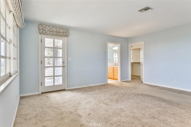 empty room featuring carpet flooring, a healthy amount of sunlight, and visible vents