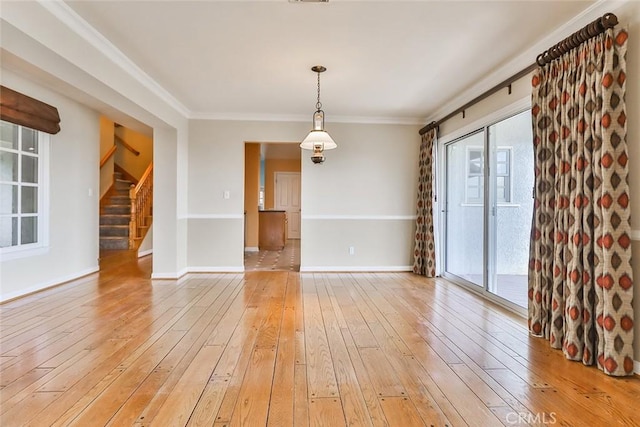 unfurnished room featuring light wood-type flooring, baseboards, ornamental molding, and stairs