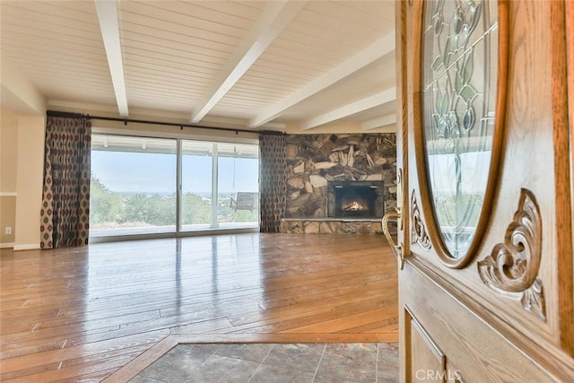 living area with beamed ceiling, wood-type flooring, and a fireplace