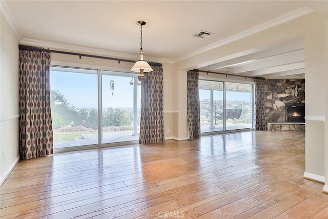 empty room with baseboards, visible vents, a fireplace, crown molding, and light wood-type flooring