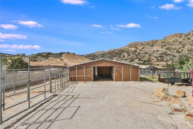 view of outdoor structure featuring an outbuilding, driveway, an exterior structure, a carport, and a mountain view