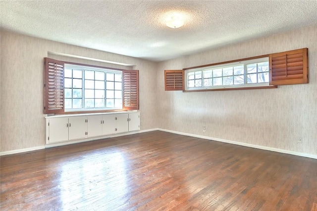 spare room with dark wood finished floors, a textured ceiling, and baseboards