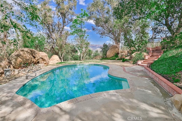 outdoor pool with stairs and a patio