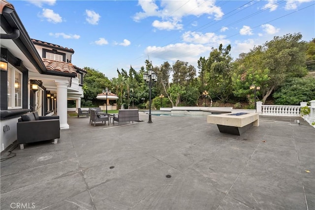 view of patio featuring an outdoor pool and an outdoor living space with a fire pit