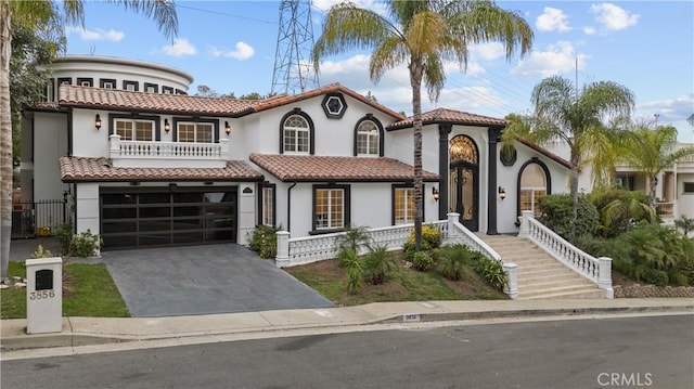 mediterranean / spanish home featuring stucco siding, concrete driveway, a balcony, a garage, and a tiled roof