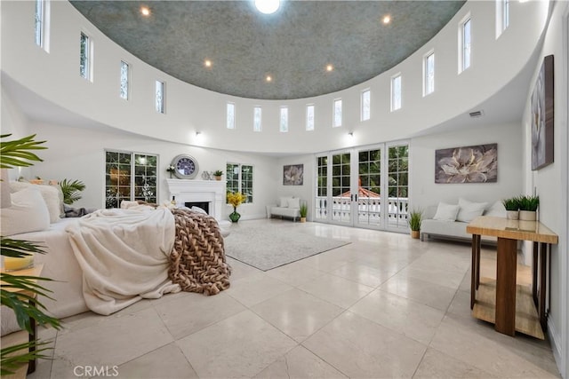 tiled living room featuring visible vents, french doors, a fireplace, and a high ceiling