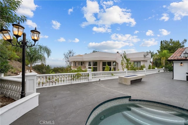 view of patio featuring a fire pit and an in ground hot tub