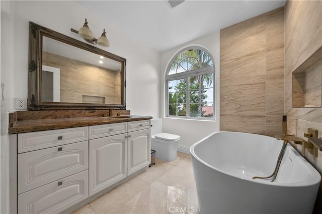 full bathroom with a freestanding bath, vanity, and toilet