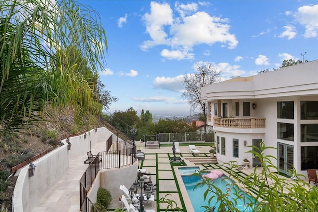 outdoor pool featuring fence and a patio