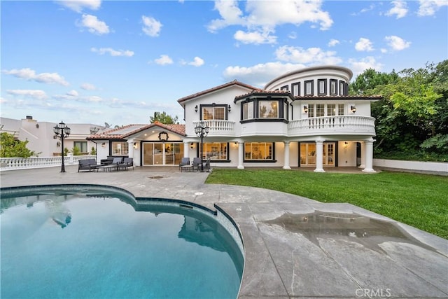 rear view of house with french doors, a balcony, fence, a yard, and a patio area