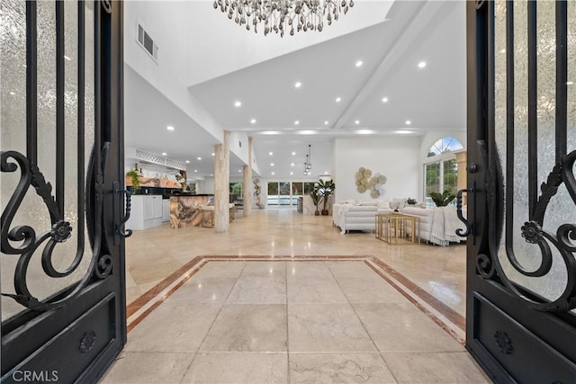 entryway with a notable chandelier, a towering ceiling, visible vents, and recessed lighting