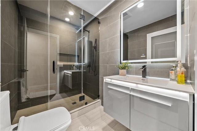 bathroom with tile walls, recessed lighting, toilet, a stall shower, and vanity