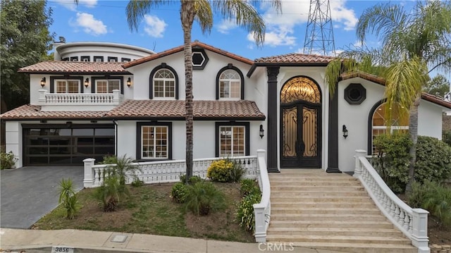 mediterranean / spanish home with a tile roof, driveway, and a balcony