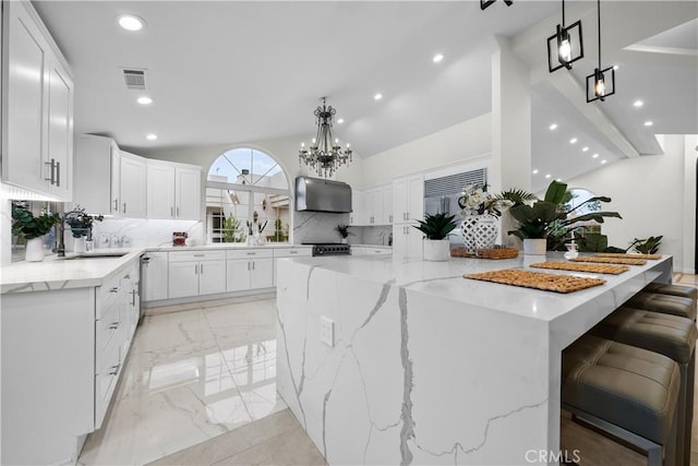 kitchen featuring visible vents, a large island, marble finish floor, vaulted ceiling, and under cabinet range hood