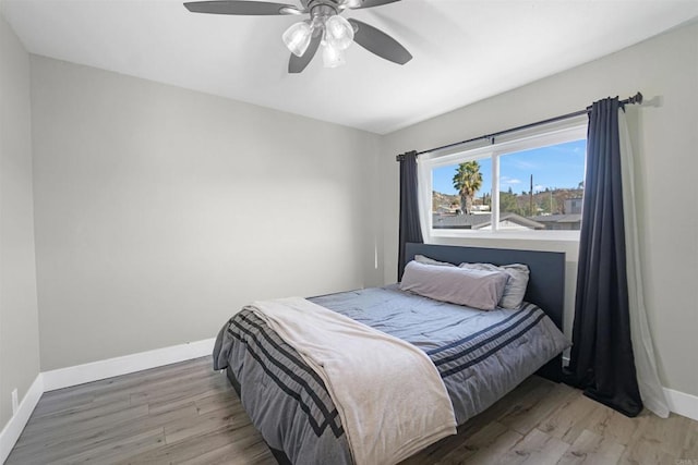 bedroom with ceiling fan, baseboards, and wood finished floors