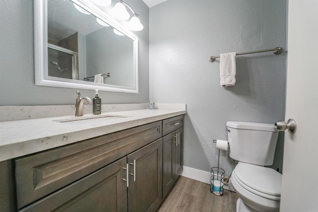 full bath with baseboards, toilet, wood finished floors, an enclosed shower, and vanity