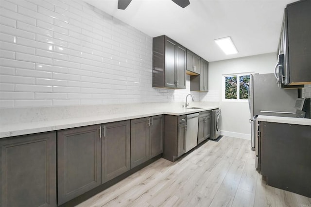 kitchen featuring washer / clothes dryer, light wood-style flooring, decorative backsplash, appliances with stainless steel finishes, and a sink