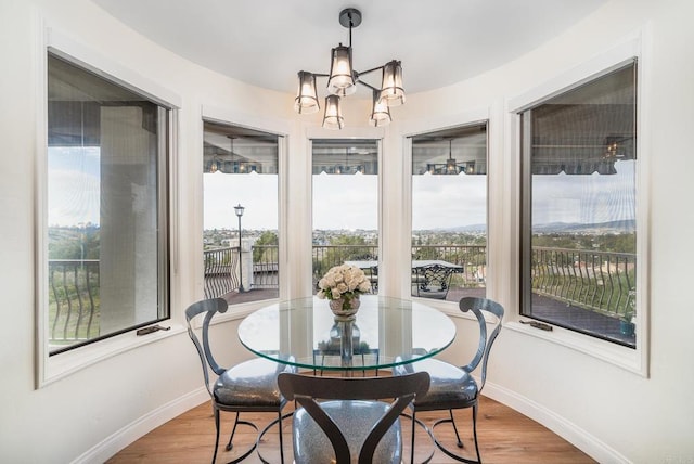 dining space featuring an inviting chandelier, wood finished floors, and baseboards