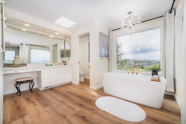 bathroom featuring a wealth of natural light, a freestanding tub, toilet, and wood finished floors