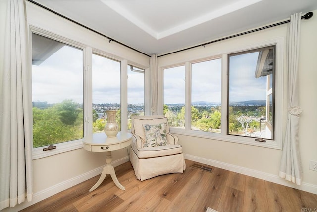 living area featuring light wood-style floors, visible vents, and baseboards