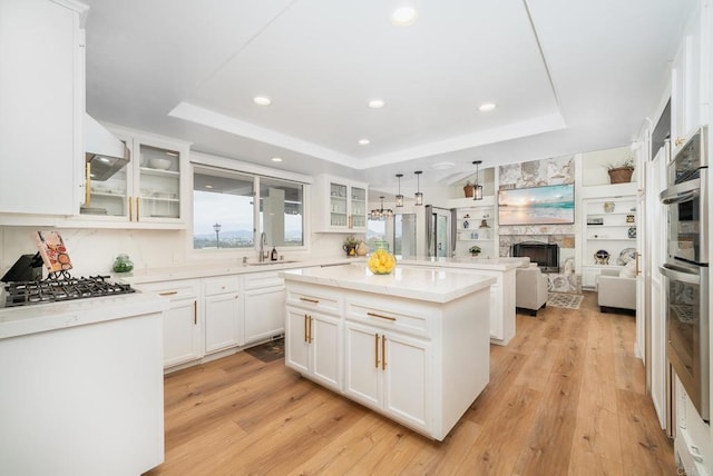 kitchen featuring a center island, light wood-type flooring, a tray ceiling, and a sink