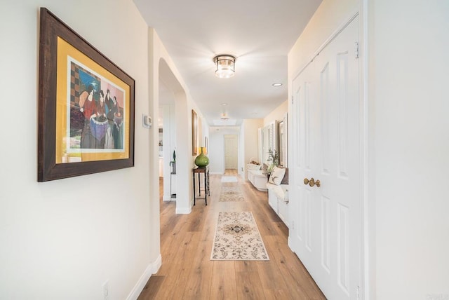 corridor featuring baseboards and light wood-style flooring