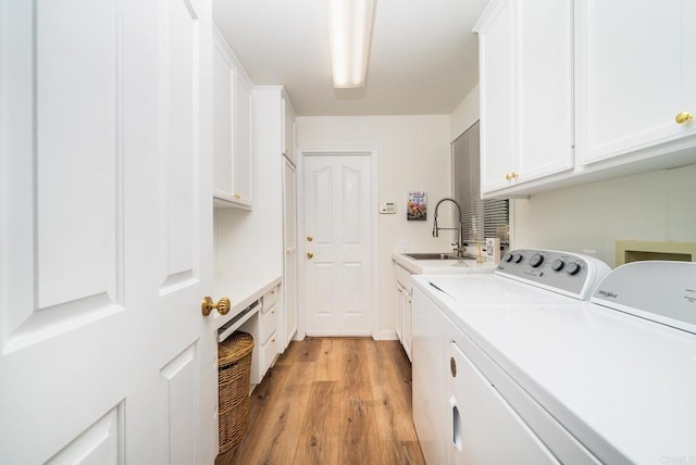 clothes washing area featuring washer and clothes dryer, cabinet space, light wood finished floors, and a sink