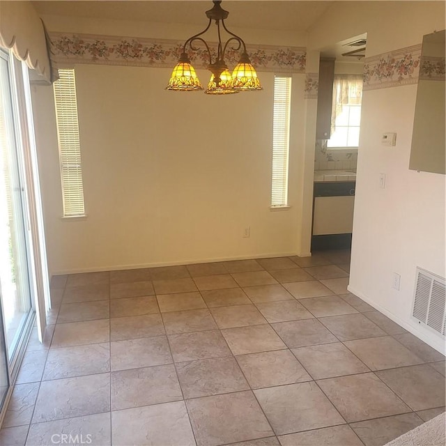 empty room with an inviting chandelier, baseboards, light tile patterned floors, and visible vents