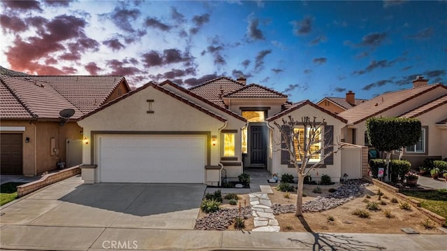 mediterranean / spanish-style house with a garage, driveway, a tile roof, and stucco siding