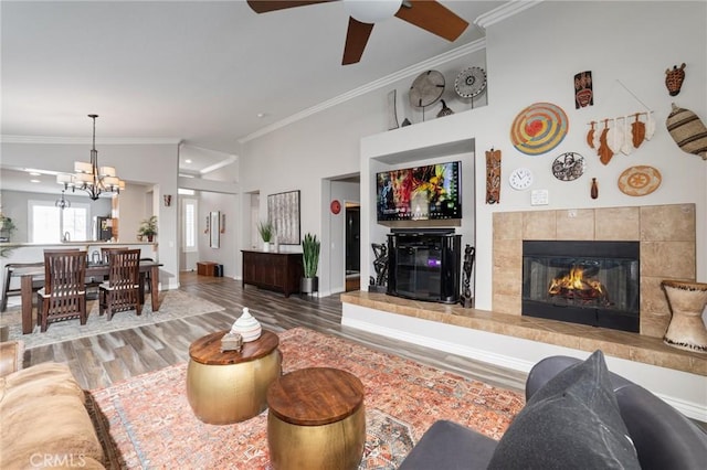 living area with ornamental molding, a fireplace, an inviting chandelier, and wood finished floors