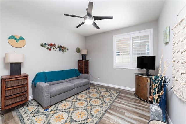 living room featuring ceiling fan, wood finished floors, and baseboards