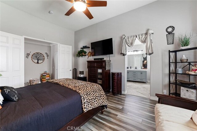 bedroom with ceiling fan, connected bathroom, baseboards, and wood finished floors