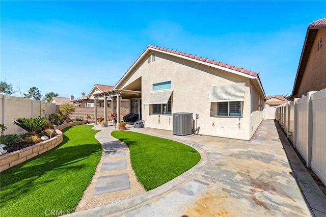 rear view of house featuring a patio area, a fenced backyard, central AC, and stucco siding