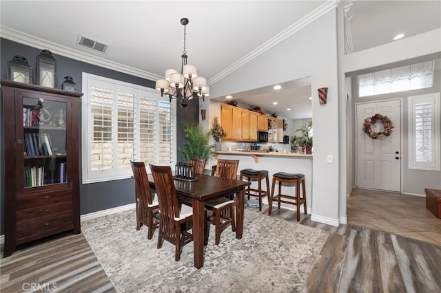 dining room featuring visible vents, an inviting chandelier, ornamental molding, wood finished floors, and baseboards