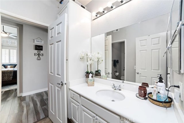 bathroom with toilet, baseboards, wood finished floors, and vanity