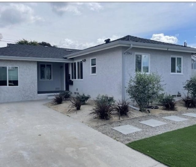 view of front of property featuring roof with shingles and stucco siding