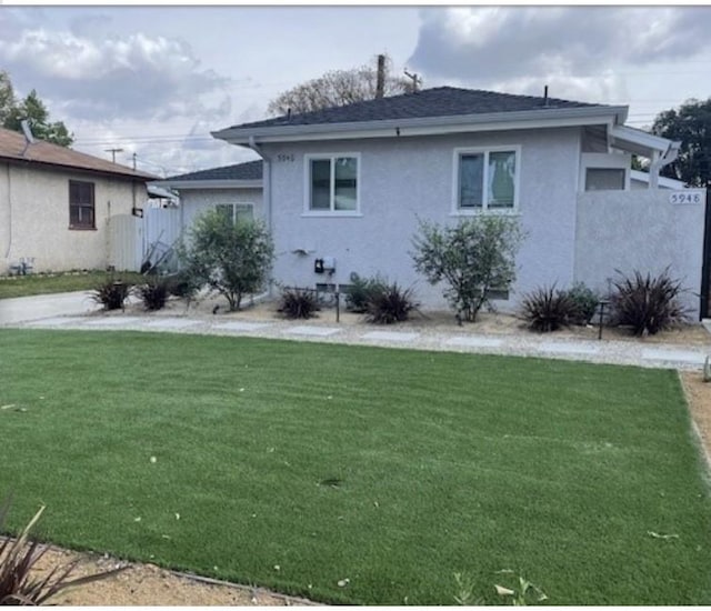 rear view of house with a lawn and stucco siding